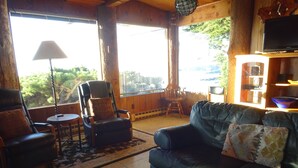 A cozy living room with a leather sofa, a recliner, and a small round table. - Heart Stopping Ocean Views, Secluded Getaway, Whale Watching (Little River)