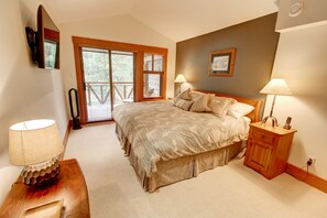 A bedroom with a large bed, two bedside lamps, a wooden nightstand, and a wall-mounted TV. - Whistler Mountainside Ski-In Ski-Out Spectacular Views (Whistler)