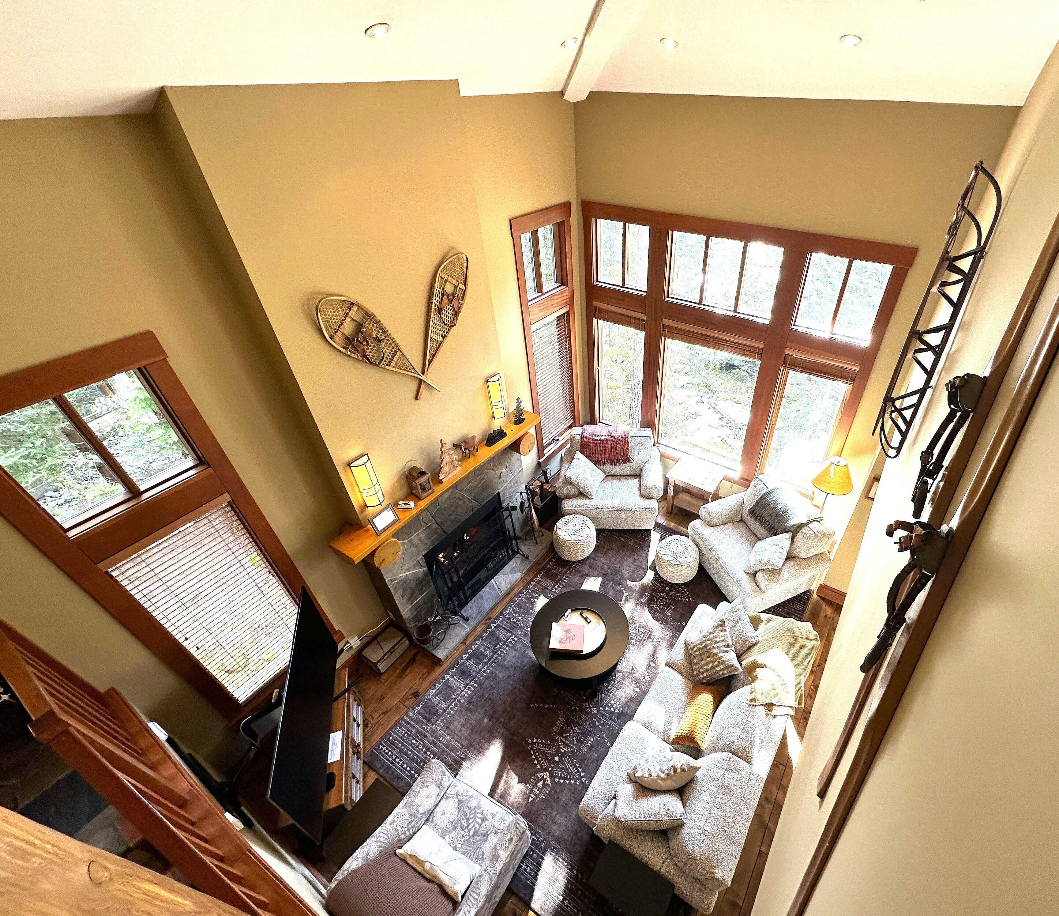 A spacious living area with a fireplace, comfortable seating, and large windows offering views of the outdoors.