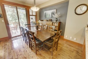 A dining area with a wooden table, chairs, a chandelier, a bookshelf, and a clock on the wall. - Whistler Mountainside Ski-In Ski-Out Spectacular Views (Whistler)