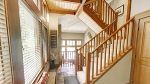 A wooden staircase leading to a landing with a stone floor and a view of the outdoors. - Whistler Mountainside Ski-In Ski-Out Spectacular Views (Whistler)
