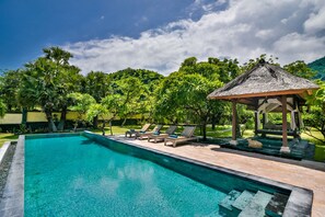 A clear swimming pool with lounge chairs and a gazebo. - Exotic Beachfront Villa in the Serene North (Pemuteran)