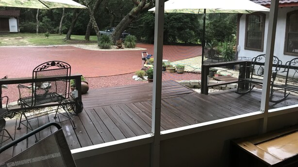 A covered outdoor area with a wooden deck, metal chairs, and umbrellas. - Lets Go Camping In Comfort, Southern Style, come on down. (Summerdale)