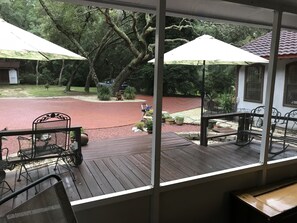 A covered outdoor area with a wooden deck, metal chairs, and umbrellas. - Lets Go Camping In Comfort, Southern Style, come on down. (Summerdale)