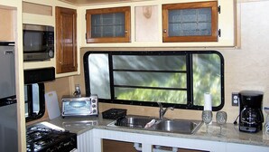 A compact kitchen with a microwave, toaster, sink, and a window with a view. - Lets Go Camping In Comfort, Southern Style, come on down. (Summerdale)