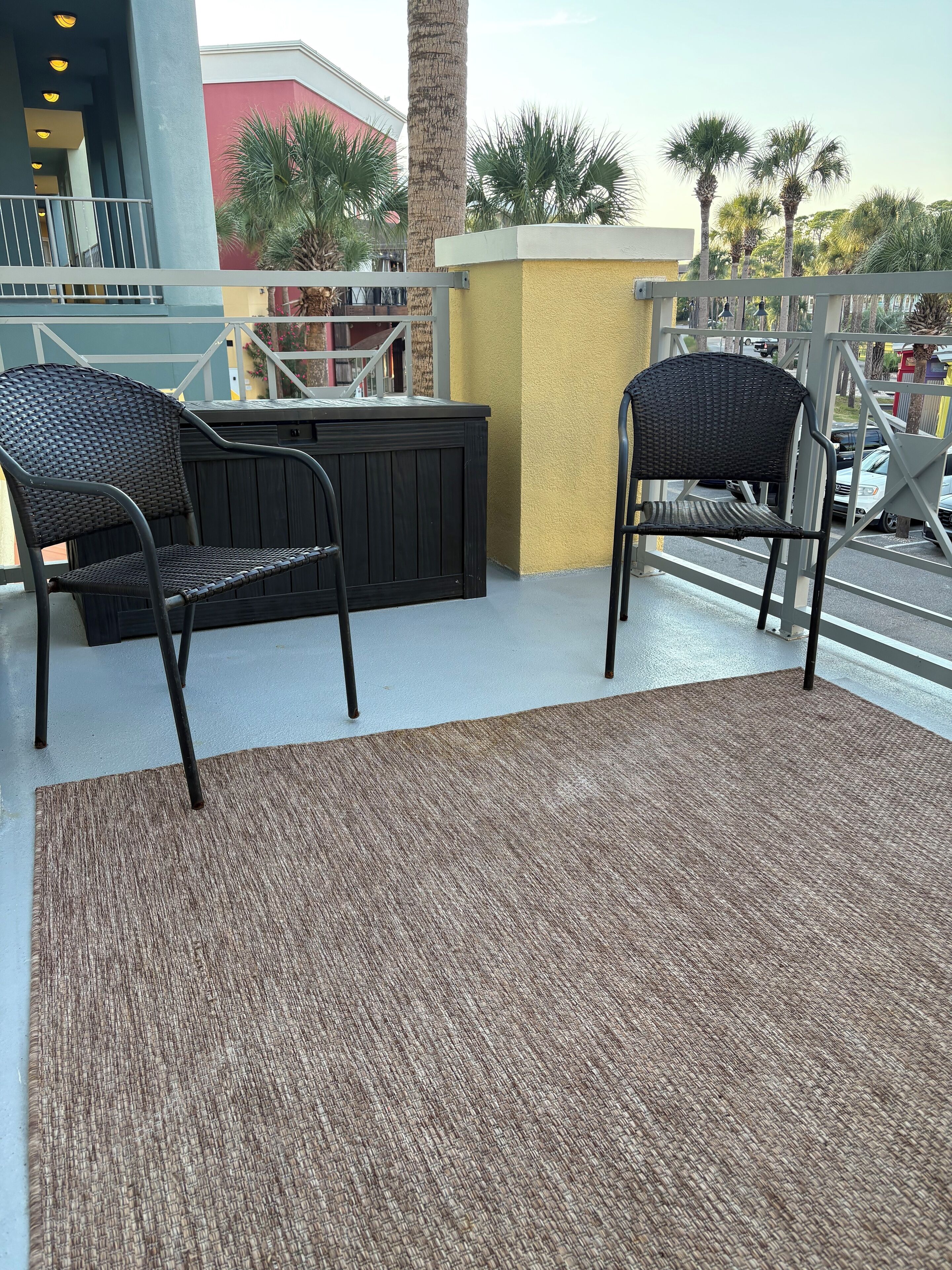 Ein Balkon mit zwei Korbstühlen und einem braunen Teppich.