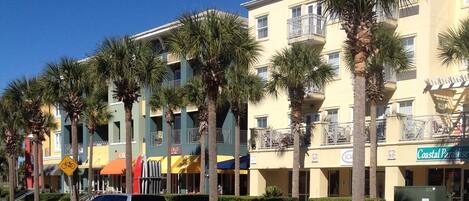 A multi-story hotel with balconies, palm trees, and a sign for 'Coastal Paradise'.