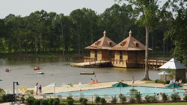 A lakeside resort with wooden cabins, a swimming pool, and docked boats. - The Guesthouse at The Waters, Walk to Chapel, Pool & Town Square (Pike Rd)