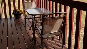Une terrasse en bois avec une table et des chaises, d’où l’on a vue sur un quartier résidentiel, avec des maisons et des montagnes en arrière-plan.