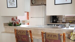 Une cuisine moderne dotée d’un îlot central, de chaises en bois avec un revêtement coloré et d’un plancher en bois.