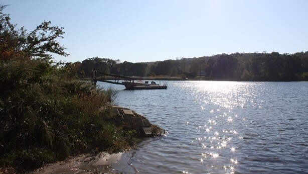 A calm lake with a dock extending into the water, surrounded by dense foliage and a clear sky. - PRIVATE HOME NEAR BEACH LOCATED IN NARRAGANSETT, RI (Narragansett)