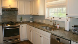 A kitchen with white cabinets, a granite countertop, stainless steel appliances, and a window with blinds. - PRIVATE HOME NEAR BEACH LOCATED IN NARRAGANSETT, RI (Narragansett)