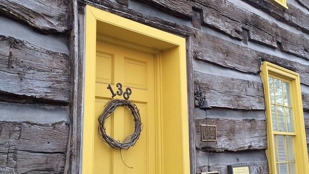 A log cabin with a yellow door, a wreath, and historical plaques. - Thaddeus Stevens' Gettysburg Log Home (Gettysburg)
