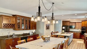 A spacious kitchen with wooden cabinets, a large island, and pendant lighting. - The Perfect Green Lake Family Getaway (Green Lake)