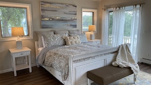 A bedroom with a bed, bedside tables, lamps, a bench, and a view of the outdoors. - The Perfect Green Lake Family Getaway (Green Lake)