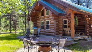 A log cabin with a patio, outdoor seating, and a fire pit. - Steps to the River! River Edge Cabin (West Glacier)