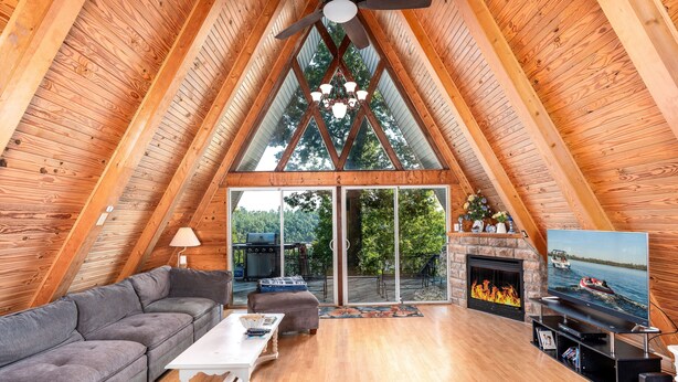 A spacious loft with a high ceiling, wooden beams, a fireplace, a TV, and a view of the outdoors. - 4 Bedrooms, Heated Private pool, hot tub, Game room, and Water Front View! (Monticello)