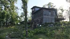 Een moderne houten chalet met een ruim terras en een trap naar een tweede verdieping.