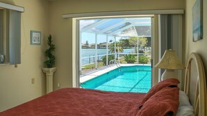 Une chambre dotée d’un grand lit, offrant une vue sur une piscine et comprenant un patio couvert.
