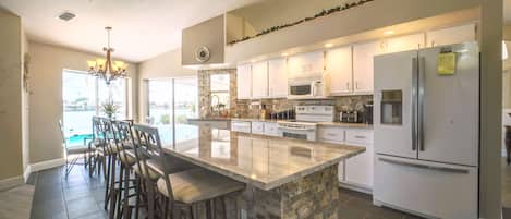 A spacious kitchen with a large island, modern appliances, and a view to the outside.