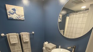 Une salle de bain avec un mur bleu, des toilettes blanches, un lavabo blanc et un miroir.