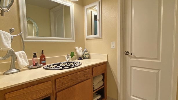 Une salle de bain équipée d’un lavabo, d’un miroir, d’un porte-serviettes et d’une porte.