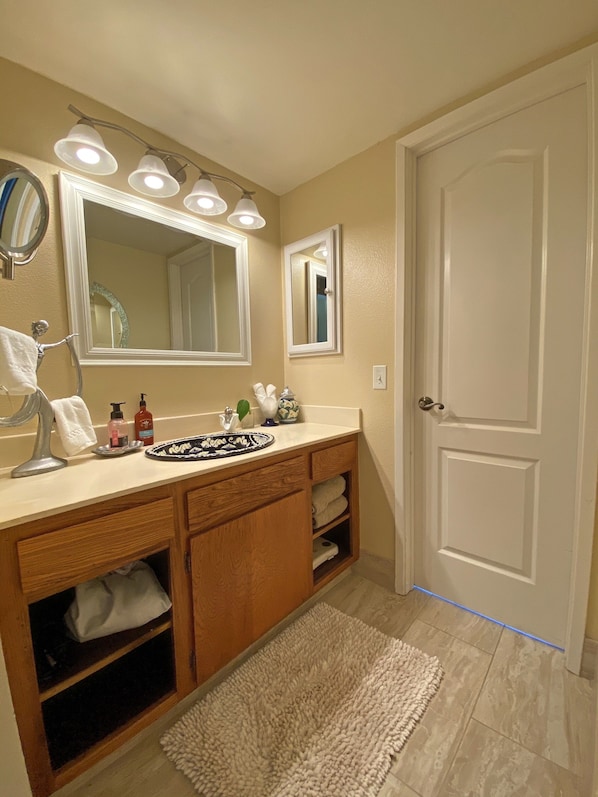 Une salle de bain équipée d’un lavabo, d’un miroir, d’un porte-serviettes et d’une porte.