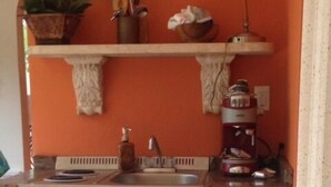 Een kleine keuken met een inbouwvaatwasser, een spoelbak en een koffiezetapparaat.