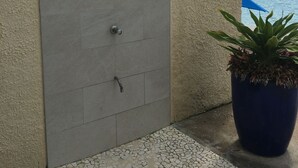 A grey door with a shower, a no parking sign, and a potted plant on a tiled floor. - Oceanfront -on 7 Mile Beach- 1  Bed-Cayman Reef Resort # 21 Sleeps 4,   (Seven Mile Beach)