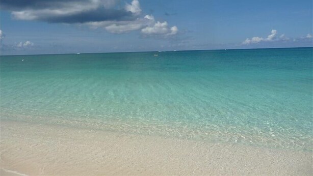 A beach with clear turquoise water and a sandy shore. - Oceanfront -on 7 Mile Beach- 1  Bed-Cayman Reef Resort # 21 Sleeps 4,   (Seven Mile Beach)