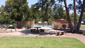 A pool area with a brick wall, a red umbrella, and a picnic table. - Charming Tubac Villa located within Tubac Golf Resort (Tubac)