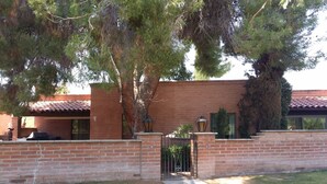 A brick house with a tiled roof, a gated entrance, and a well-maintained lawn. - Charming Tubac Villa located within Tubac Golf Resort (Tubac)