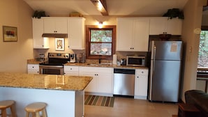 A modern kitchen with white cabinets, stainless steel appliances, and a granite countertop. - Relaxing Cozy Cabin in the Heart of the Blue Ridge Mountains. Pet friendly (Foscoe)