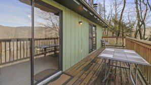 A wooden deck with a table and chairs, a sliding glass door, and a small outdoor seating area. - Relaxing Cozy Cabin in the Heart of the Blue Ridge Mountains. Pet friendly (Foscoe)