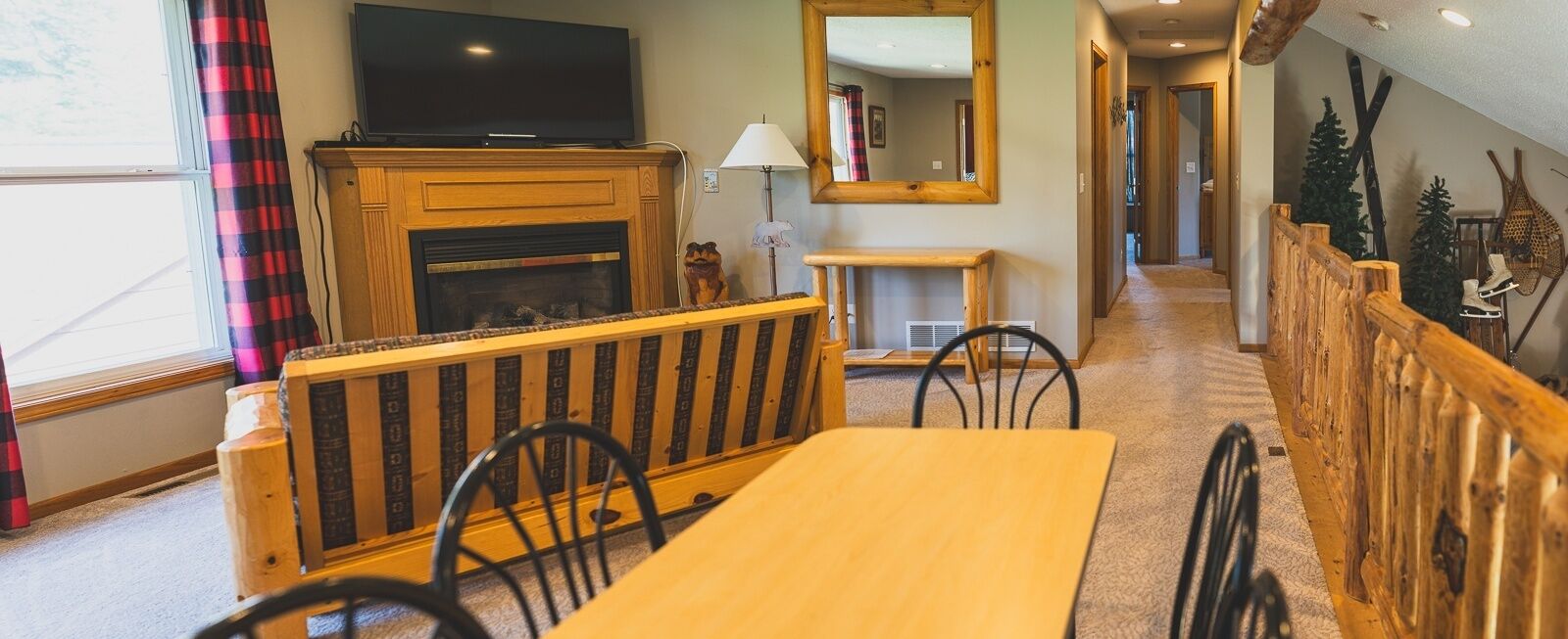 A cozy living room with a fireplace, a television, and a dining area with a wooden bench and table.