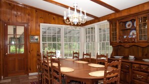 A dining room with a wooden table, chairs, and a chandelier.