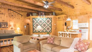 Un interior acogedor de cabaña con detalles de madera, una zona de comedor y una kitchenette.