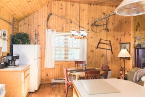 Un chalet rustique en bois comprenant un coin cuisine, une table à manger et un espace de vie chaleureux.