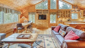 Interior de una cabaña de madera con comedor, cocina y sala de estar.