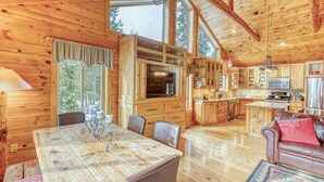 Interior de una cabaña de madera con comedor, cocina y sala de estar.