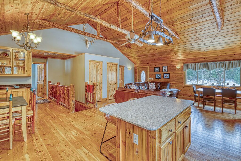Interior espacioso de una cabaña de madera con una isla de cocina grande, una mesa de comedor de madera y un rincón de estar acogedor.