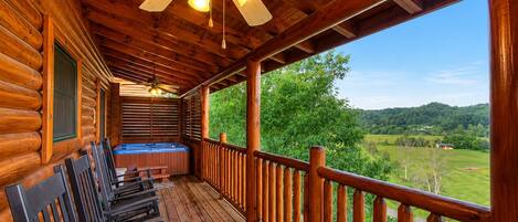 Una cabaña de madera con balcón, jacuzzi y vistas al campo.