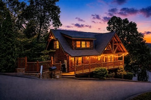 A log cabin with a porch, a mailbox, and a stone wall.