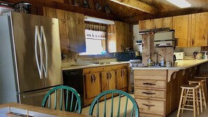 Une cuisine en bois dotée d’un îlot central, d’un réfrigérateur et d’une table à manger avec des chaises.
