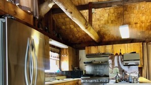 Une cuisine avec un plafond en bois, un réfrigérateur en acier inoxydable, une cuisinière et des armoires en bois.