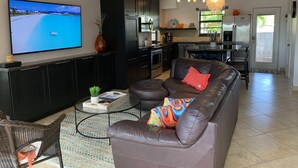 Un salon moderne avec un grand téléviseur à écran plat, un canapé en cuir marron et une table basse.