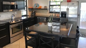 Une cuisine moderne dotée d’appareils électroménagers en acier inoxydable, d’un îlot central et d’un luminaire décoratif.