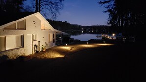 A house with a garage, a driveway, and a dock extending into a lake. - Lake Front Getaway, Family Friendly. (Mooresville)