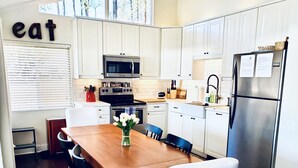 A modern kitchen with white cabinetry, a wooden dining table, and a refrigerator. - Lake Front Getaway, Family Friendly. (Mooresville)