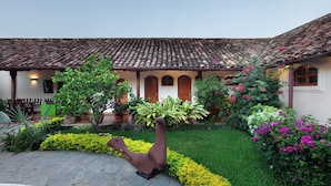 Un edificio tradicional con tejado de tejas, un patio cubierto y un jardín bien cuidado con diversas plantas y flores.